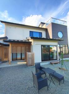 a house with chairs and a table in front of it at Fujiyoshida house, 2 toilet 2 bathroom, Mt Fuji view, 4 living room, free parking 5 cars, projector, washmachine, pet ok in Minamitsuru