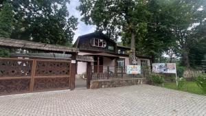 a house with a wooden gate and a building at Hotel Dumbrava in Şoldăneşti