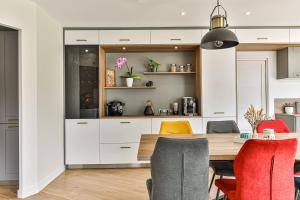 a kitchen with white cabinets and a wooden table and chairs at Villa Sylvia avec piscine intérieure et espace bien-être in Landevieille