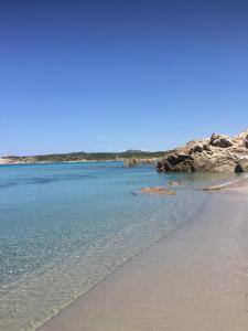 a sandy beach with rocks in the water at Monolocale a Rena Majore di Gallura in Rena Majore