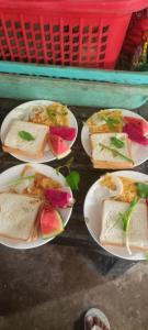four plates of sandwiches on a table with a basket at Joes Homestay in Siem Reap