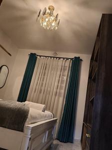 a bedroom with a green curtain and a chandelier at Homely Homes in Eldoret