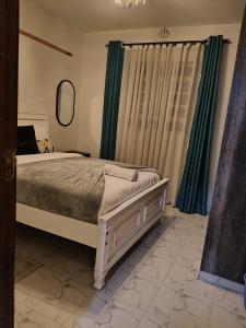 a bedroom with a bed and green curtains at Homely Homes in Eldoret