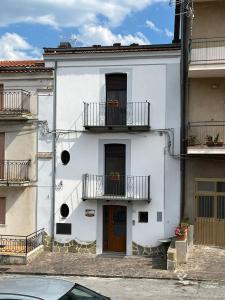 a white building with two balconies and a door at Affittacamere Dietro al Convento in San Martino dʼAgri