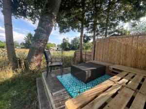 a wooden bench with a chair next to a tree at Ibiza chalet in natuurlijke omgeving in Bergen op Zoom +11 photos
