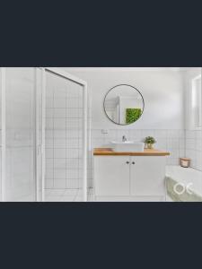 a white bathroom with a sink and a mirror at Tranquil Coastal Retreat - Renovated 2BR - Sea Views & Sunset Nights in Halletts Cove