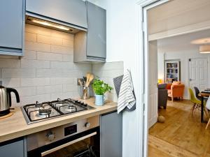 La cuisine est équipée de placards bleus et d'un four avec plaques de cuisson. dans l'établissement 5 Devon Beach Court, à Woolacombe 25 autres photos