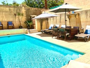 a swimming pool with a table and an umbrella at Carpe Diem in Xagħra