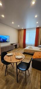 アルマトイにあるArbat Apartmentsのテーブル、椅子、ベッドが備わる客室です。
