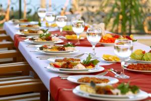a long table with plates of food and wine glasses at Hotel Armani in Mundakāyam