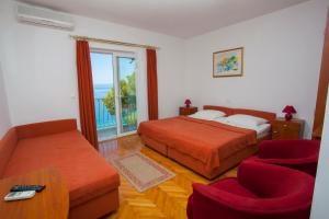 a bedroom with two beds and a couch and a window at Villa Ankora Apartments Tučepi in Tučepi