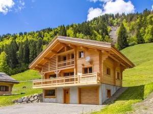 una casa di tronchi con balcone su una collina. di Le balcon de la pointe percée a Le Grand-Bornand