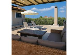 a patio with chairs and a table and an umbrella at Andriana's 3-Bedroom Countryside Retreat in Pandokrátor