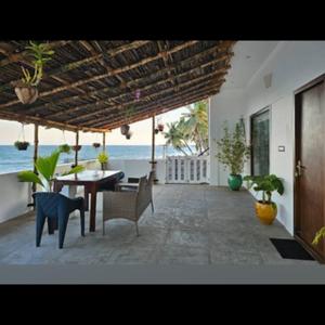 a patio with a table and chairs and the ocean at Villa Ande - Beach Homestay Pondicherry in Kālapettai