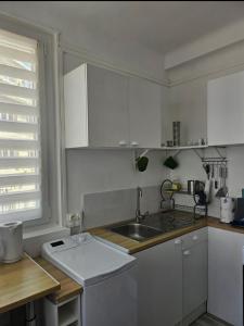 a kitchen with white cabinets and a sink and a window at La Marée in Calais