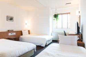 a hotel room with two beds and a tv at Hotel Pacific Kanazawa in Kanazawa