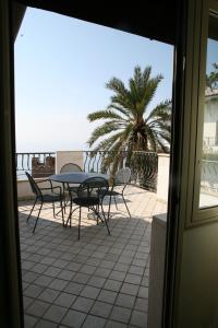 un patio con una mesa, sillas y una palmera en Hotel Vello d'Oro, en Taormina