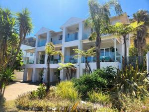 a white building with palm trees in front of it at Sea 'n Summit Hermanus in Hermanus