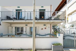 a white building with a balcony and a staircase at Monolocale Marizzola in Cala Gonone