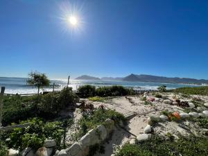 una playa de arena con el sol brillando sobre el océano en Kom Surf Studio, en Kommetjie
