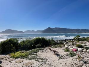 una playa con el océano y las montañas en el fondo en Kom Surf Studio, en Kommetjie