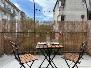een tafel en stoelen op een terras met een hek bij Appartement entier Cosy in Grenoble