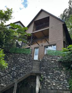 a house with a stone wall and stairs at Green Azure - მწვანე ლაჟვარდი in Kvariat'i +4 photos