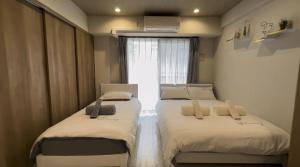 zwei Betten in einem kleinen Zimmer mit Fenster in der Unterkunft Kumo 云 in Osaka