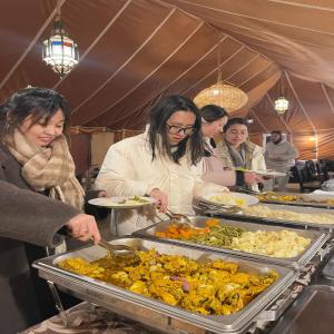 a group of people preparing food in a tent at Desert Nights Camp in Merzouga