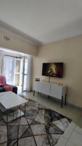 Una sala de estar con un sofá y un televisor en la pared. en Lauryl Comfy Stays, en Kisumu