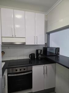 a kitchen with white cabinets and a black counter top at Playa Jardin Terrassenwohnung mit Pool , 100 Meter zum Strand in Puerto de la Cruz +5 photos