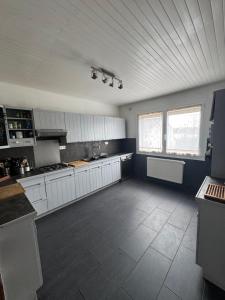 una grande cucina con armadi bianchi e pavimento piastrellato di La Casa Nancy Tomblaine 12 pers Parking et Jardin a Tomblaine