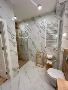 ein Bad mit weißen Marmorwänden und einem WC in der Unterkunft Apartment Paradise in Świnoujście