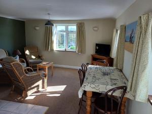 ein Wohnzimmer mit Tisch und Stühlen und einem Fernseher in der Unterkunft Old School Cottage in Toller Porcorum