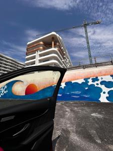 une voiture avec une peinture sur le côté d'un bâtiment dans l'établissement AXXIS Nova Resort & SPA Mamaia Nord C108, à Mamaia