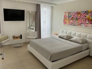 a white bedroom with a bed and a tv at Affitta camere Locarno in Minusio