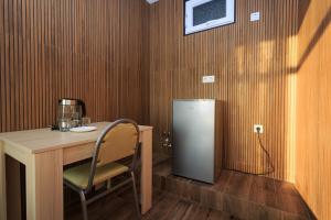 a table with a chair and a refrigerator in a room at Guest House 99 in Batumi