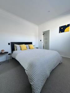 a white bedroom with a large bed with yellow pillows at Paradise Retreat in Tauranga