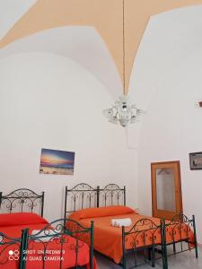 a bedroom with two beds with orange sheets and a chandelier at Casa di Angela in Sannicola +7 photos