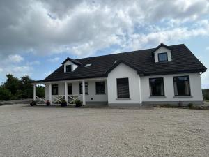 a white house with a black roof at Luxury Galway Getaway with 5 Bedrooms in Galway