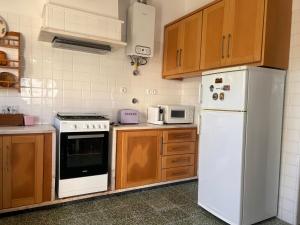 a kitchen with a white refrigerator and wooden cabinets at Ninho da Irene in Vieira de Leiria