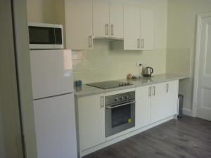 a white kitchen with white cabinets and a microwave at Apartments On Grey in Glen Innes