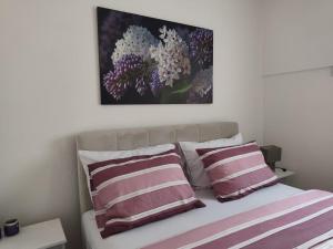a bed with two pillows and a painting above it at Apartment Lilac Sarajevo in Sarajevo
