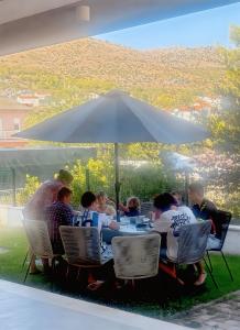 a group of people sitting at a table under an umbrella at Arte Oliva in Grebaštica