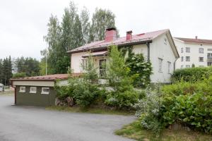 a white house with a green garage at Omakotitalo Jyväskylän keskustassa in Jyväskylä