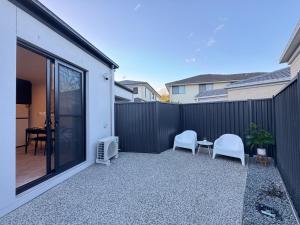 a patio with two chairs and a table and a fence at Luxe 2B2B Stay Walk to Sunnybank market square in Brisbane