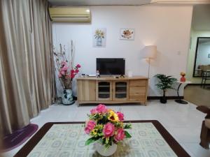 a living room with a tv and flowers on a table at RIVERBANK SUITE with riverfront mountain DUN view in Kuching