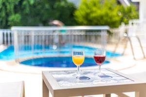 two glasses of wine sitting on a table next to a pool at Sezin Apart in Marmaris