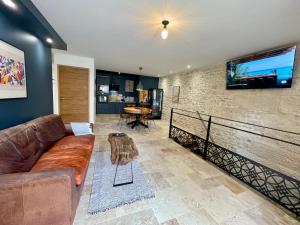 a living room with a couch and a tv on a wall at Le saint G in Augé