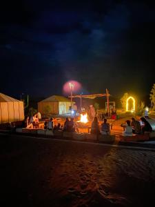 a group of people sitting around a fire at night at Tenere luxury camp in Merzouga
